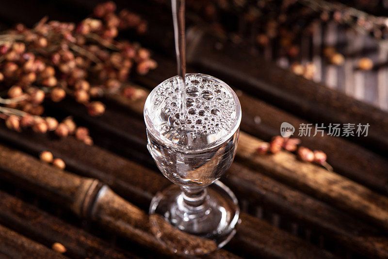 桌上的一瓶中国酒正在往杯子里倒。