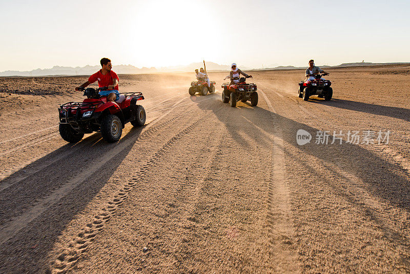 快乐的朋友们在夏天的沙漠里开着四驱车玩得很开心。