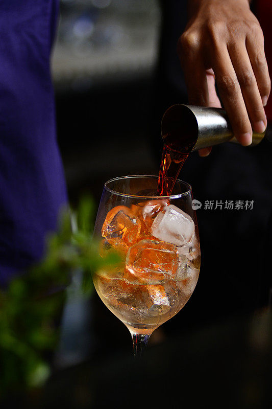 在深色背景的高级酒吧里，调酒师正在准备水果饮料。