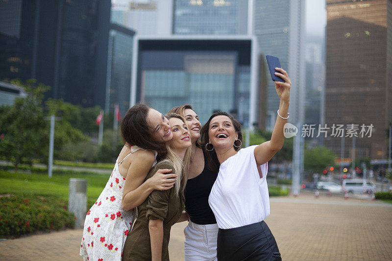 快乐的女人走在城市里，用智能手机玩得很开心