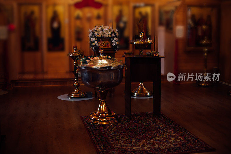传统东正教教堂内部有覆盖的洗礼池，讲坛，用白花装饰的祭坛，圣像。