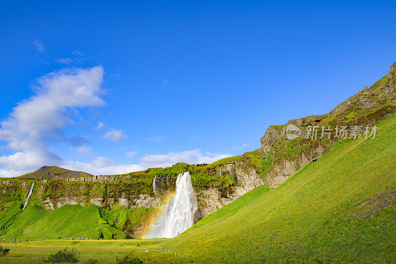 冰岛南部的Seljalandsfoss瀑布与彩虹的侧宽视图