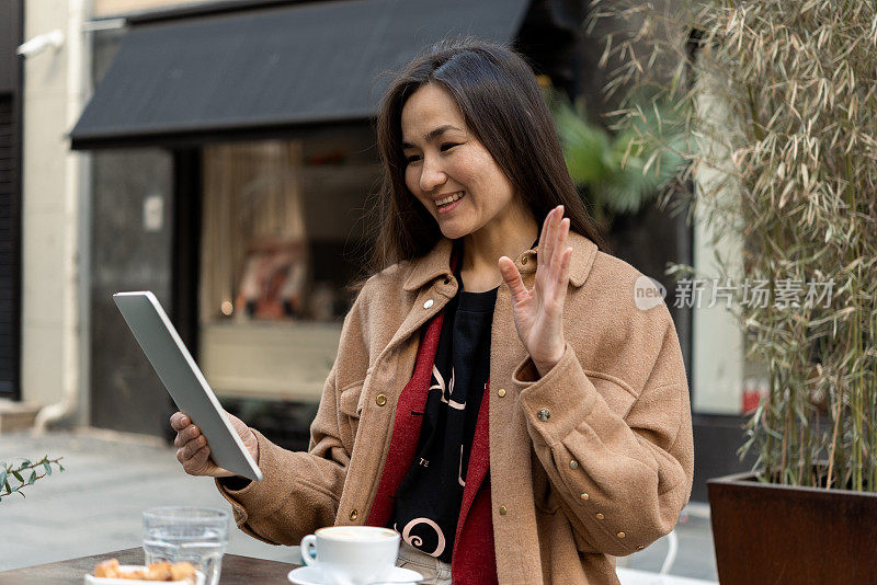亚洲妇女在咖啡馆用平板电脑打视频电话