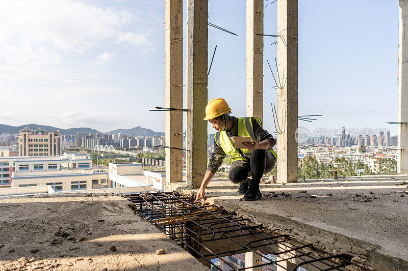 一位建筑工地的女工程师正在用平板电脑工作