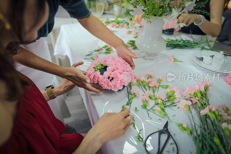 一位亚洲妇女正在上插花课，她用许多康乃馨做了一束心形的花，送给母亲庆祝母亲节。