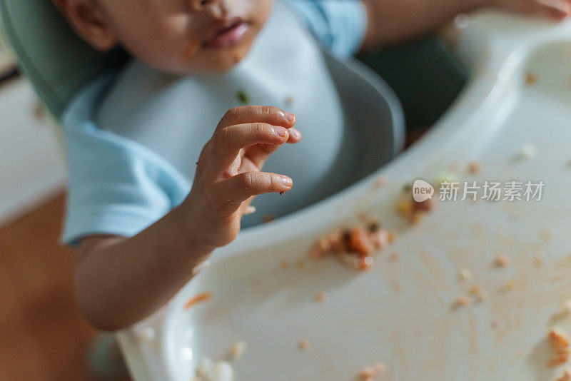 凌乱的宝宝用手自己喂奶。婴儿主导断奶(BLW)概念