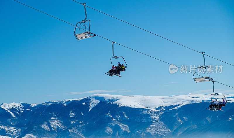 在冬天一个晴朗的日子里，滑雪缆车从白雪皑皑的山上飞过