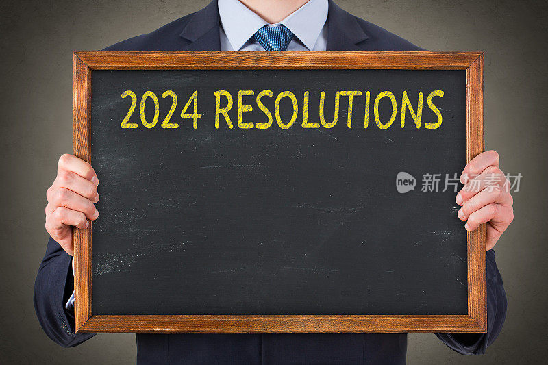 商务人士在黑板背景上书写2024年新年决心