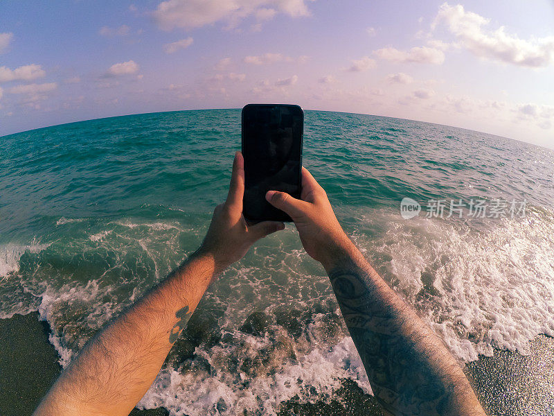 一个人在海边玩他的智能手机