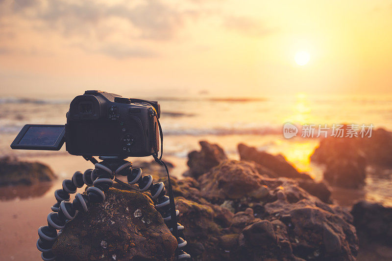 数码单反相机捕捉日出的海滩景色。