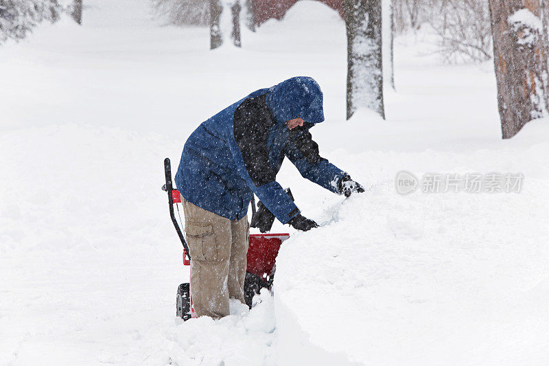 吹雪机的年轻人在暴风雪中挖雪堆