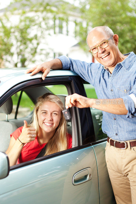 快乐的父母把车钥匙交给青少年司机垂直