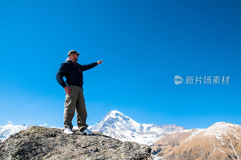 登山者站在指向山顶的岩石上