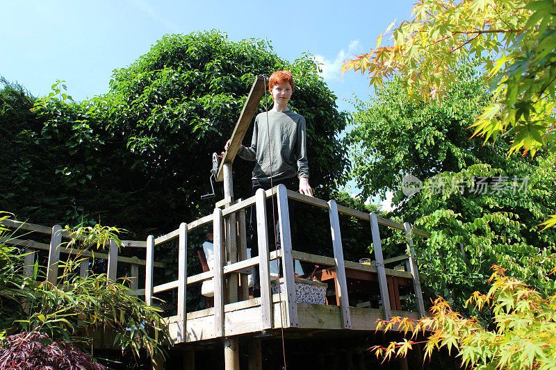 一个男孩站在花园里高高的树屋上