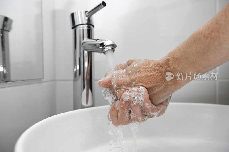有人在白色的水槽和银色的水龙头里洗手