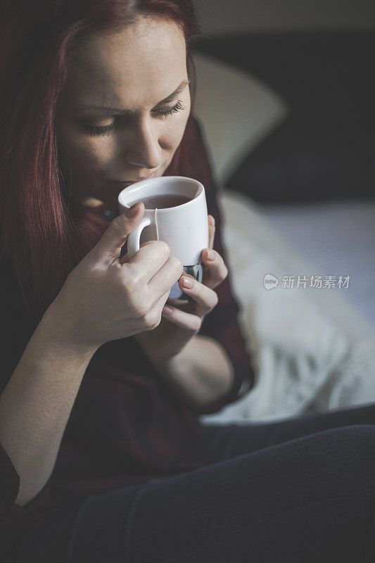 年轻女子在床上悠闲地喝着茶