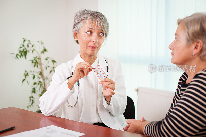 女医生拿着药片在老病人面前