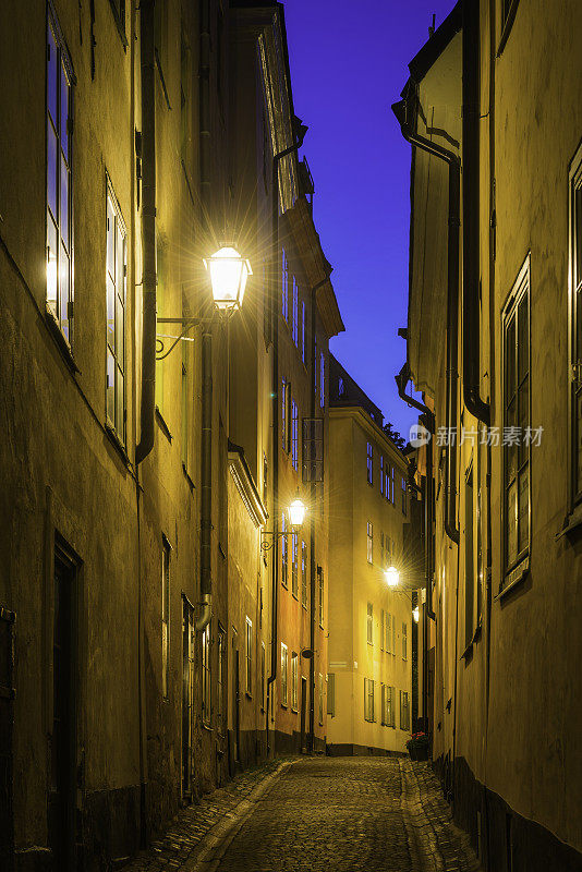 温暖的灯光照亮了瑞典斯德哥尔摩格拉斯坦风景如画的鹅卵石街道