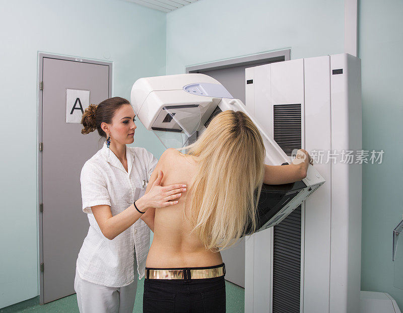 x光技术员正在给一位年轻女性做乳房x光检查