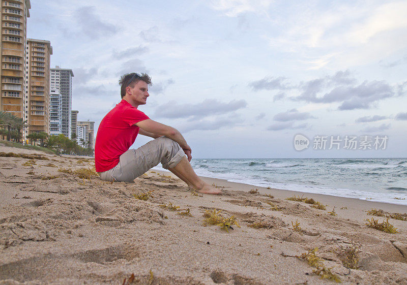 坐在迈阿密海滩上的体贴的年轻人