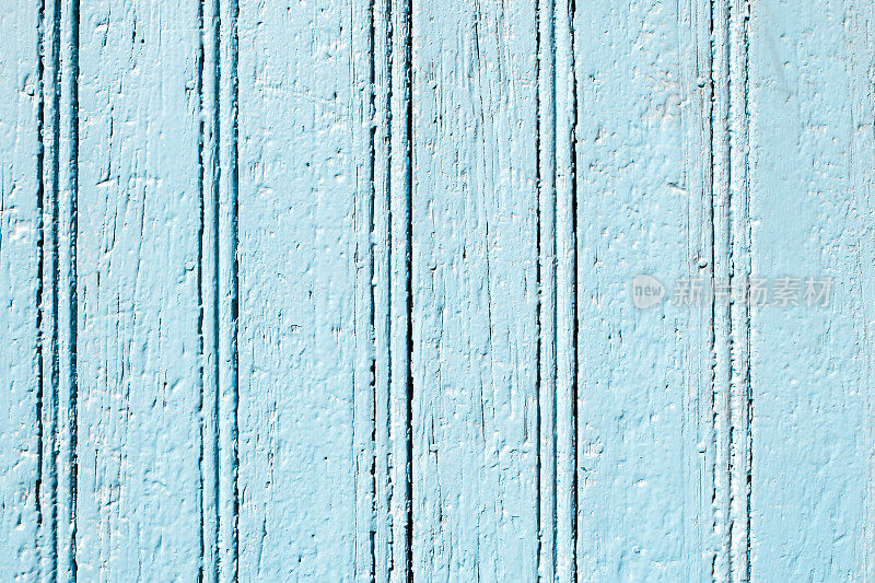 在一排风化漆成蓝色的墙壁上的垂直木板