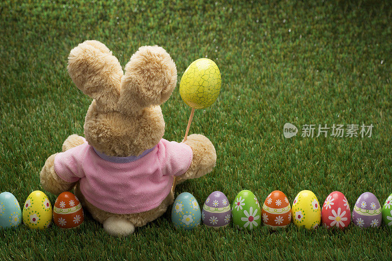 许多彩色复活节彩蛋在绿色草地上与兔子
