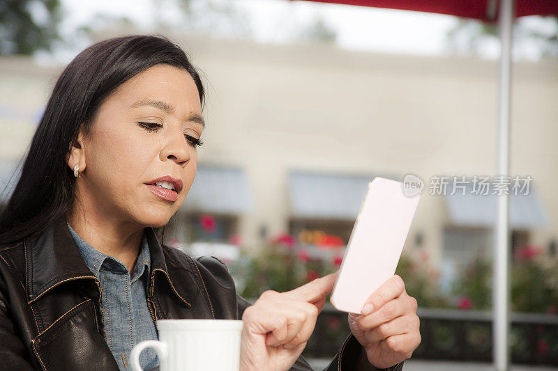 一个在户外咖啡店用手机的女人。