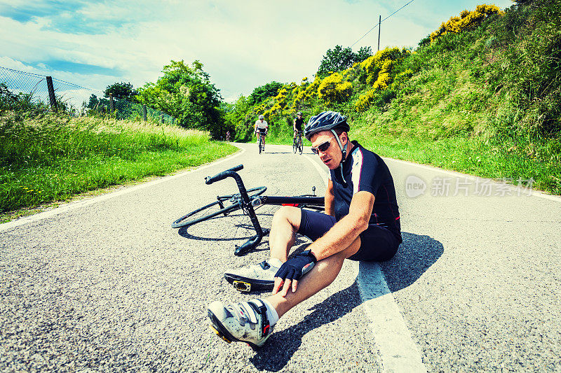 精疲力竭的骑自行车的人在路中间休息