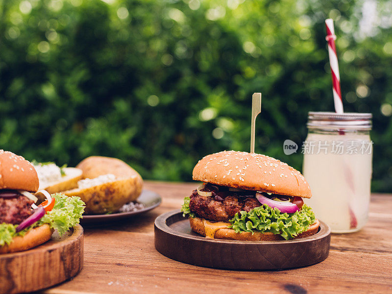 后院的桌子上有美味的奶酪汉堡和夏季饮料