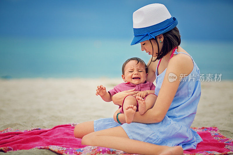 在海滩上，女孩抱着她哭泣的小妹妹