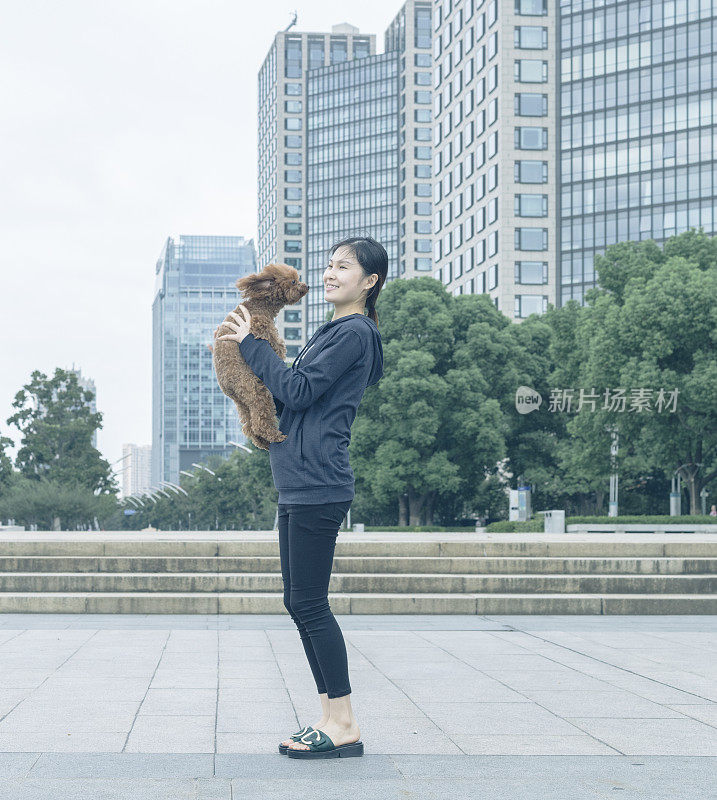 一个女人和她的小狗在城市广场上玩耍