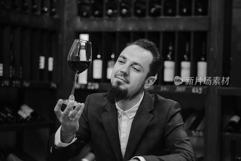 年轻侍酒师在酒窖里喝红酒