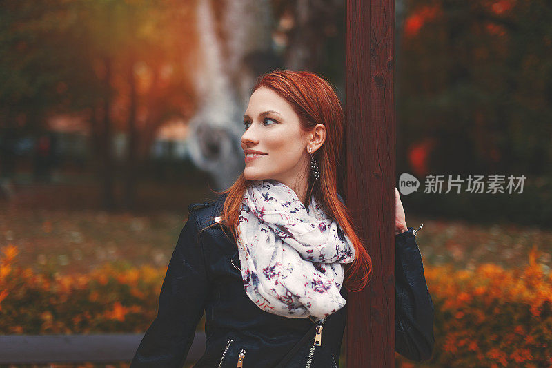 年轻时髦的红发女人看着别处的秋天