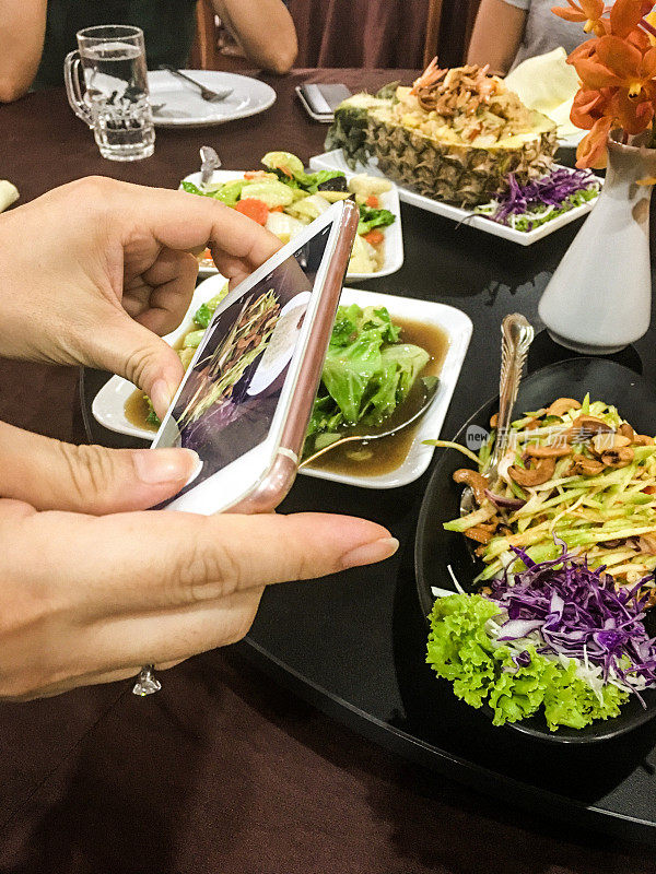 一名女子用智能手机拍下泰国美食并发布到社交媒体上