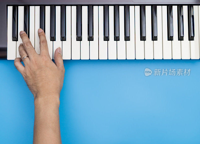 一只手弹奏音乐键盘上的键与蓝色的拷贝空间