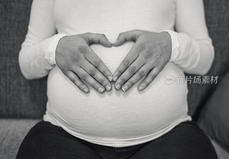 一个女人在她怀孕的肚子上做了一个心形