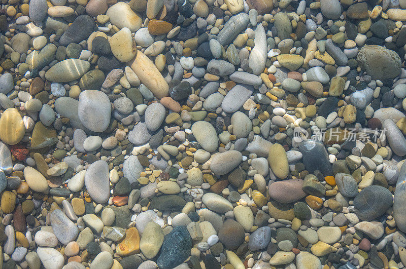 海卵石滩上有五颜六色的石头，浪花上有泡沫