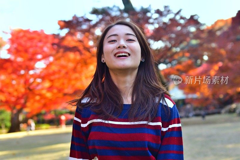 在东京的公园里，一名年轻的日本女子摆弄着她的长发