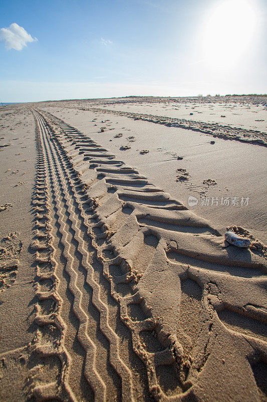 沙滩上的拖拉机轮胎痕迹。透视和消失点。