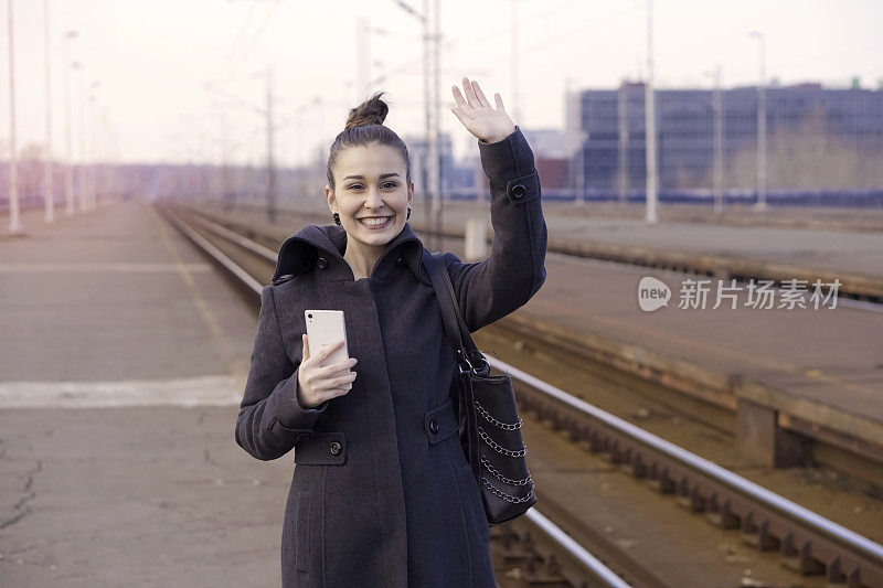 一个年轻女子在火车站用智能手机