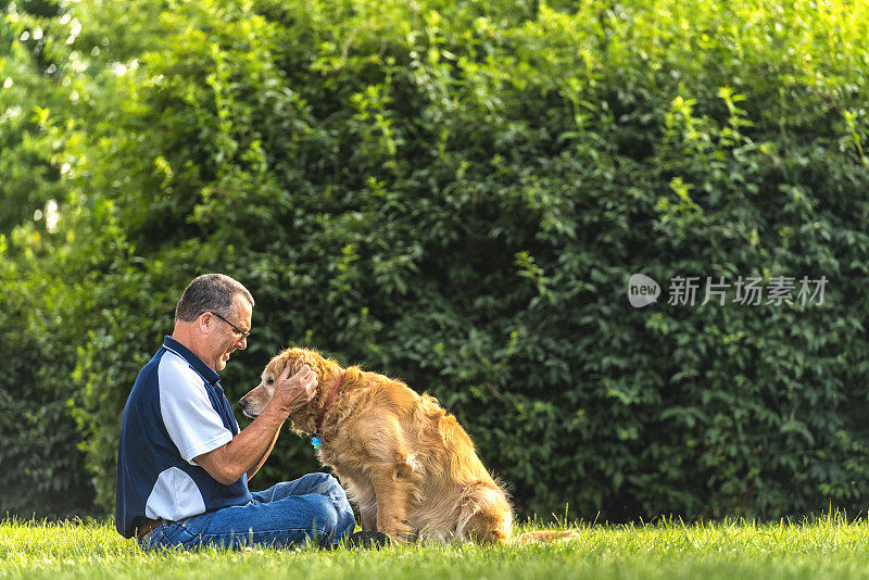 日落时分，一个男人在给他的狗揉耳朵