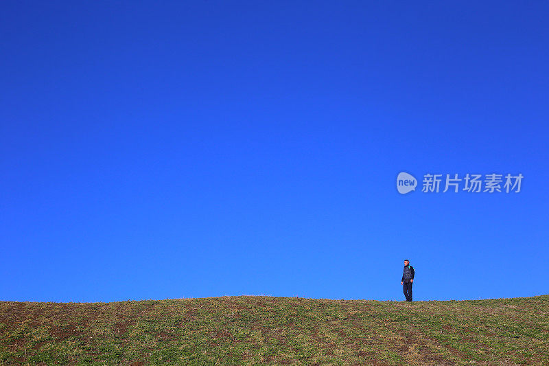 在美丽的，阳光明媚的秋日，成年徒步者在草地上的地平线