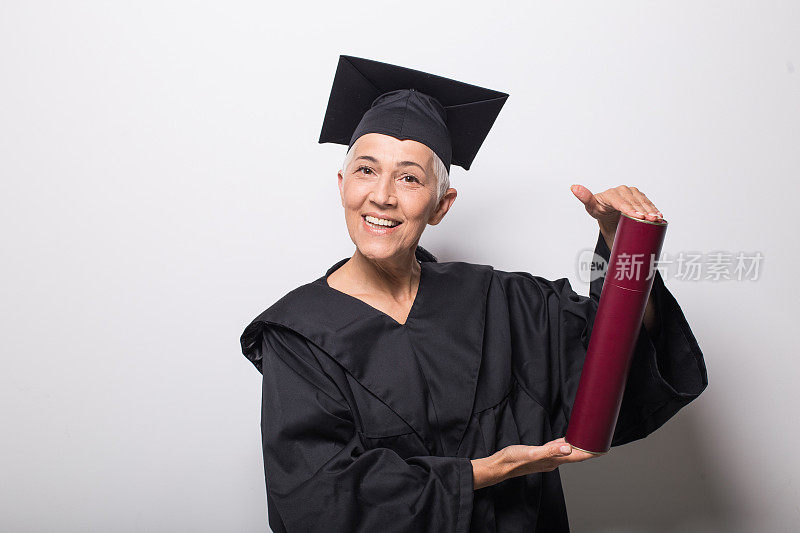 微笑的女人拿着大学文凭，穿着毕业礼服