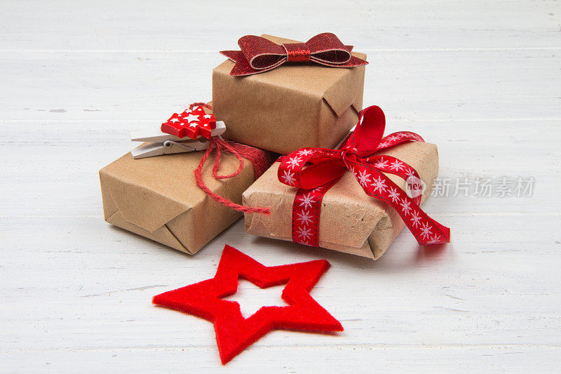 牛皮纸盒子，带红丝带。圣诞礼物在白色破旧的木制背景