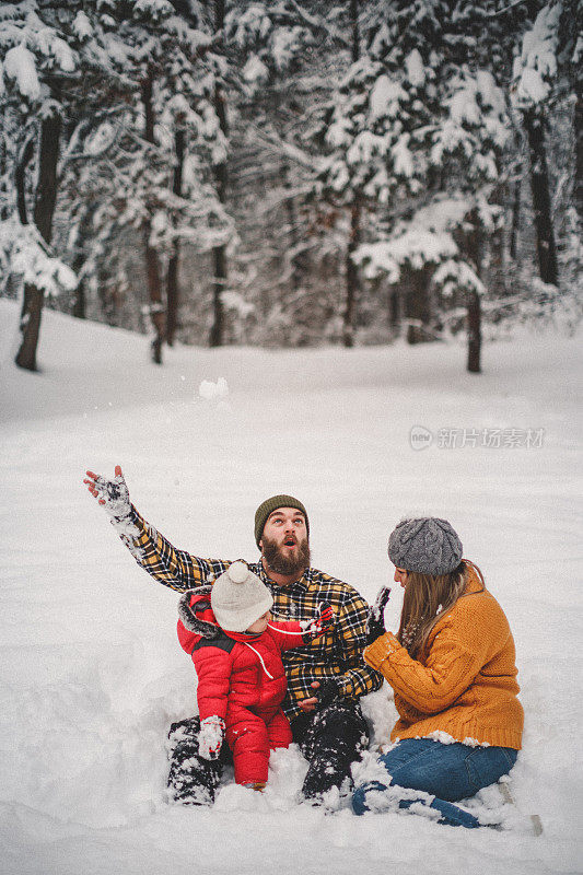 一个年轻的家庭和小男孩在雪中玩耍