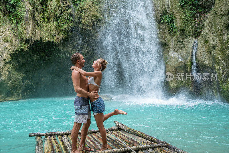 一对年轻夫妇凝视着美丽的热带瀑布