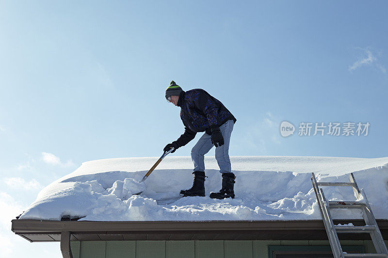 一名男子正在铲屋顶上的积雪
