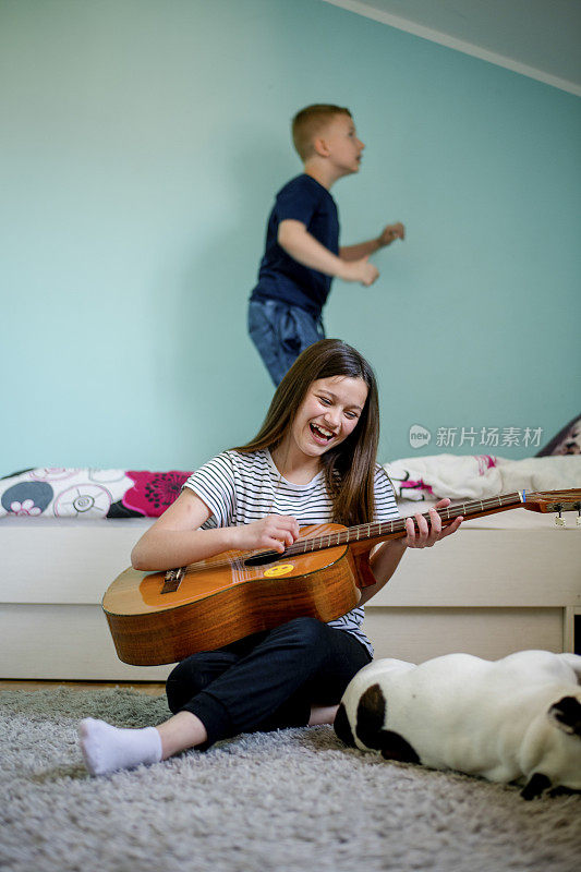 一个女孩在家里给她弟弟弹吉他