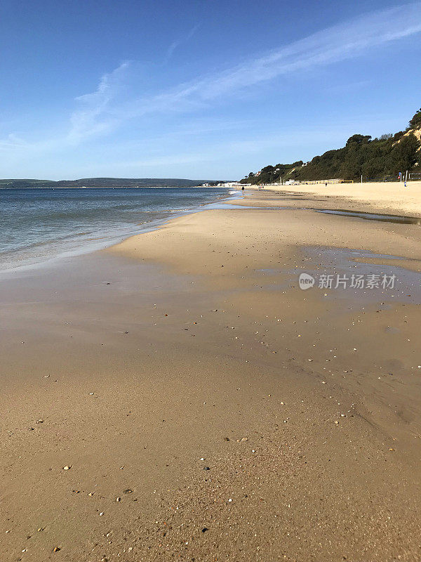 金色的沙滩，大海和阳光明媚的蓝天在伯恩茅斯英国海岸线，阿尔姆中国海滩的南部侏罗纪海岸线，伯恩茅斯，多塞特，沙滩上的阳光与海浪拍打海岸和蓝天照片，低潮