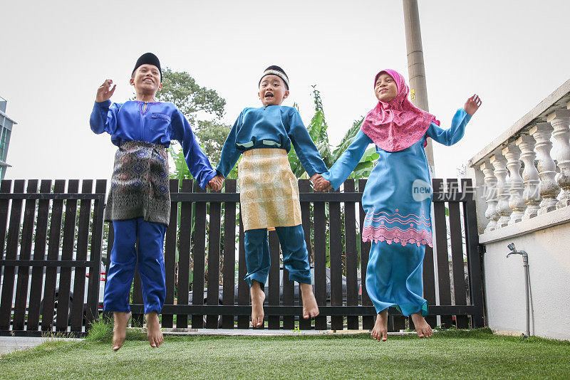 马来穆斯林兄弟姐妹穿着马来传统服装，在户外玩耍